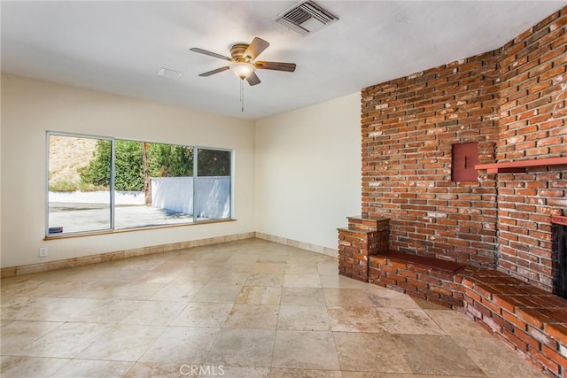 unfurnished living room featuring ceiling fan and a brick fireplace