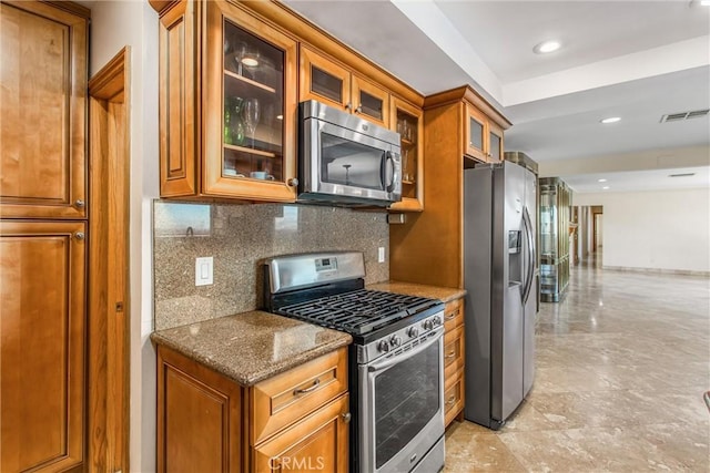 kitchen with decorative backsplash, stainless steel appliances, and dark stone counters