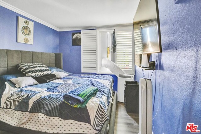 bedroom with ornamental molding and dark hardwood / wood-style floors