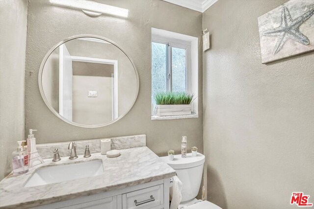 bathroom with ornamental molding, vanity, and toilet