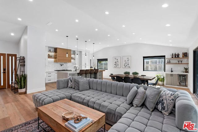 living room with vaulted ceiling, light hardwood / wood-style flooring, and sink