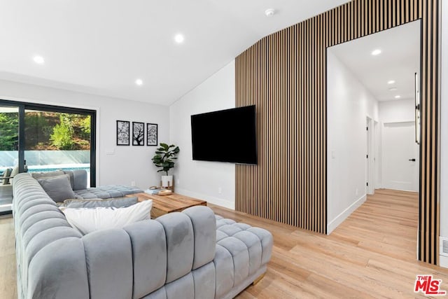 living room with light wood-type flooring and vaulted ceiling