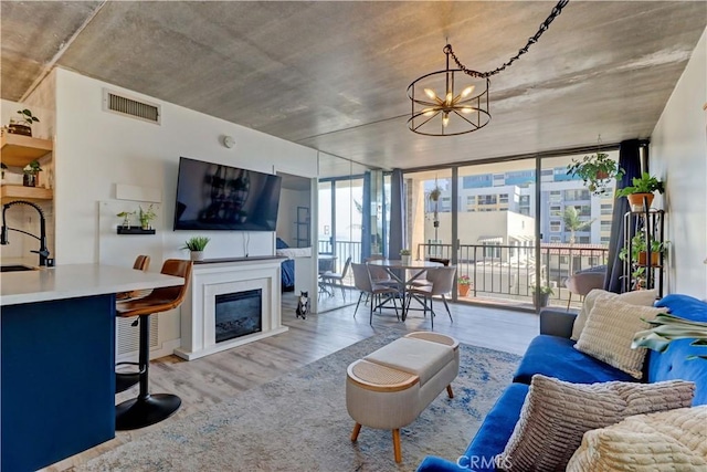 living room with sink, expansive windows, a chandelier, and light wood-type flooring