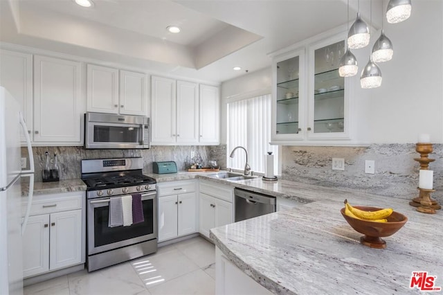 kitchen with appliances with stainless steel finishes, decorative light fixtures, tasteful backsplash, white cabinets, and a raised ceiling