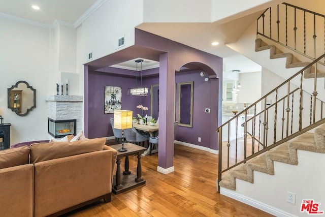 living room with crown molding, a fireplace, and hardwood / wood-style floors