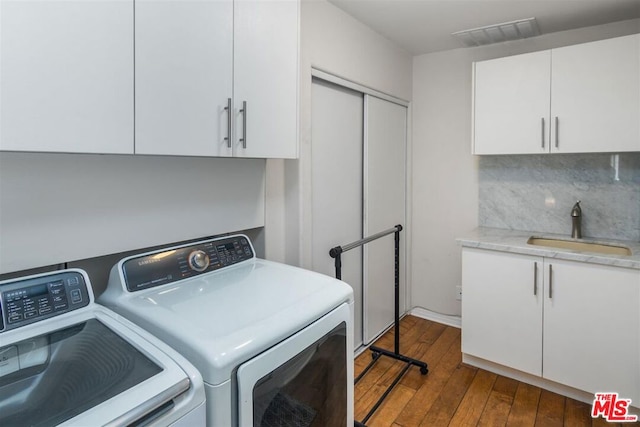 laundry room with cabinets, sink, washing machine and clothes dryer, and dark hardwood / wood-style flooring