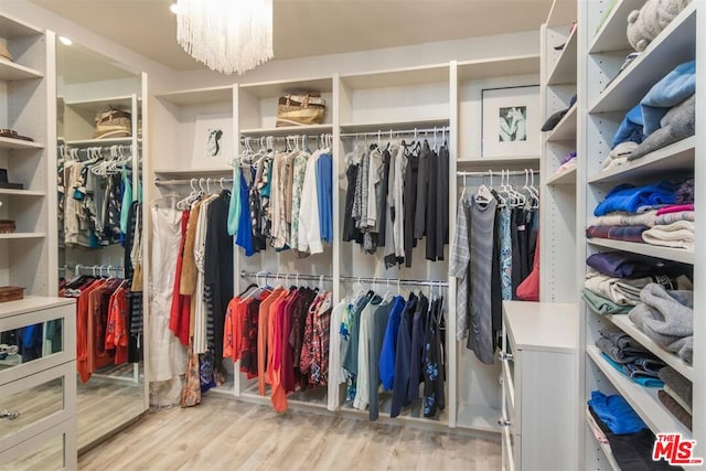 walk in closet featuring a notable chandelier and light hardwood / wood-style floors