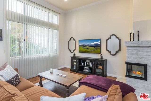 living room featuring a stone fireplace, ornamental molding, and light hardwood / wood-style floors