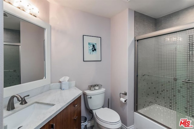 full bathroom featuring toilet, vanity, and bath / shower combo with glass door