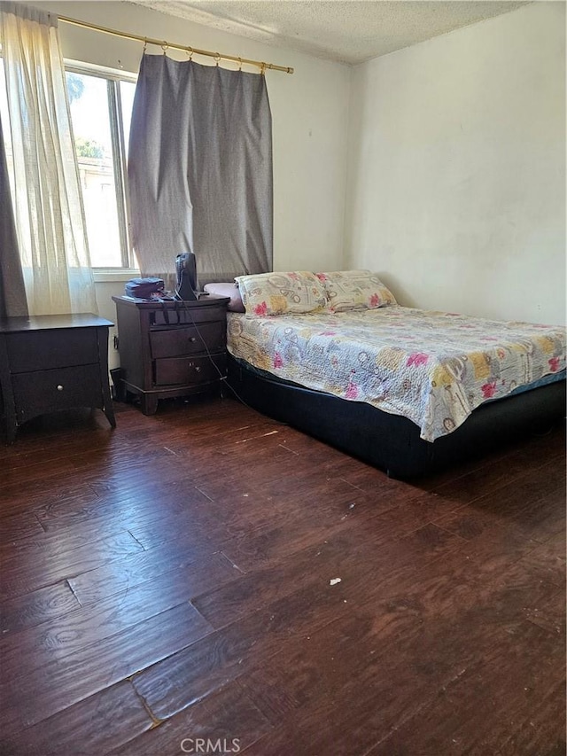 bedroom featuring a textured ceiling and dark hardwood / wood-style flooring