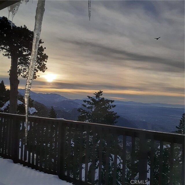 snow covered back of property with a mountain view