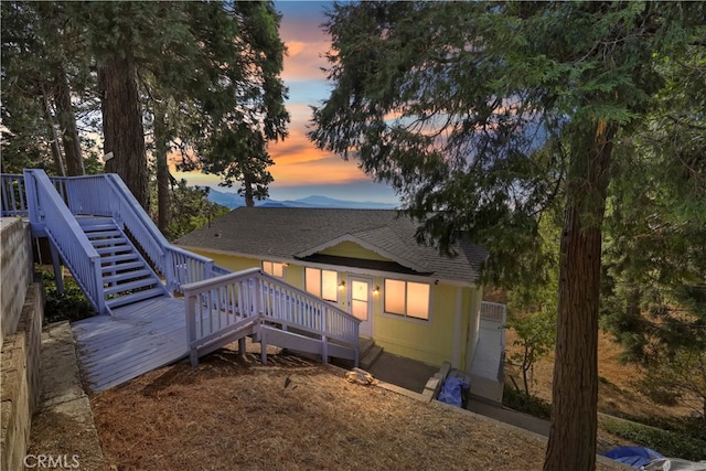 back house at dusk with a garage and a deck