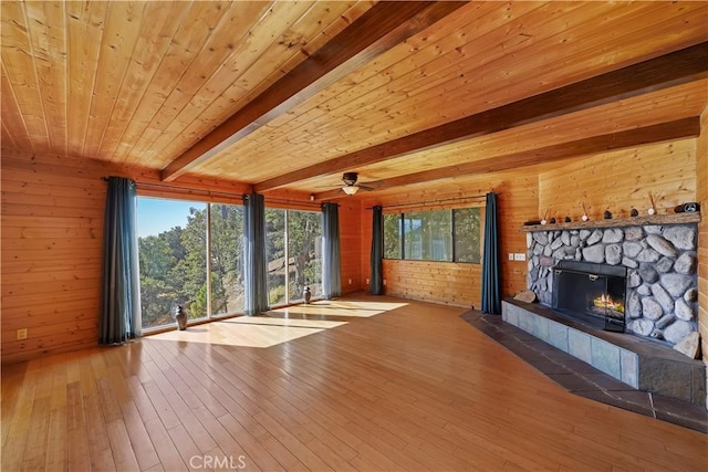 unfurnished living room featuring wood walls, beam ceiling, hardwood / wood-style flooring, and a fireplace