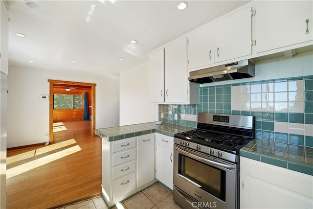 kitchen with stainless steel gas stove, tile counters, light hardwood / wood-style flooring, and white cabinetry