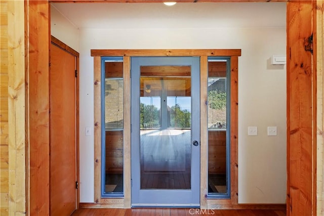 doorway with baseboards and wood finished floors