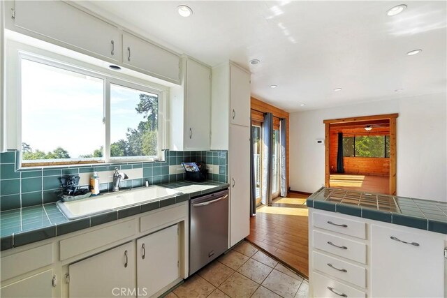 kitchen featuring tile counters, a sink, backsplash, and stainless steel dishwasher