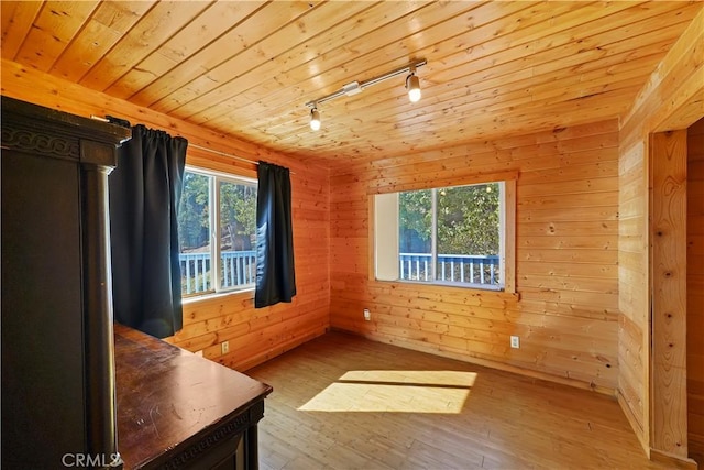 interior space with wooden ceiling, wood-type flooring, track lighting, and wood walls