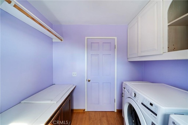 laundry room with independent washer and dryer, cabinet space, and light wood-style floors