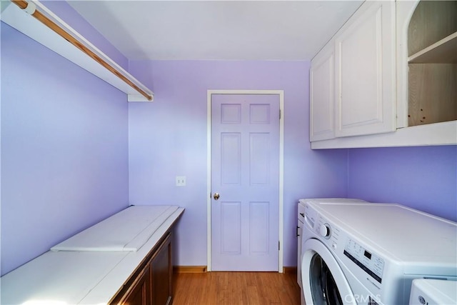 washroom featuring light wood finished floors, cabinet space, and washer and clothes dryer