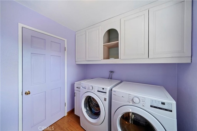 laundry area with light wood-style flooring, independent washer and dryer, and cabinet space