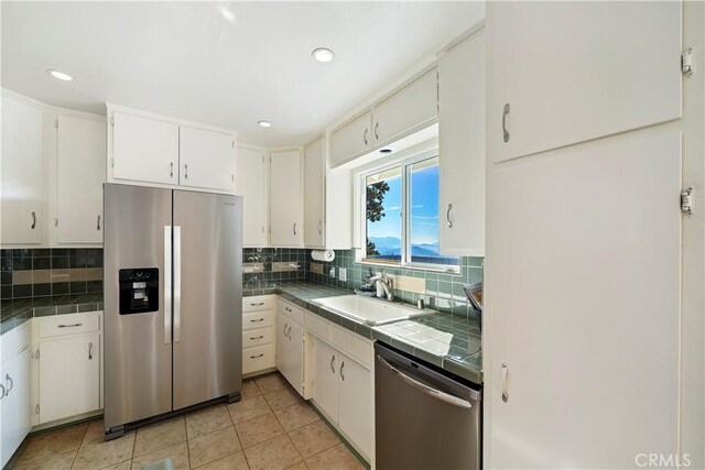 kitchen with appliances with stainless steel finishes, backsplash, and tile counters