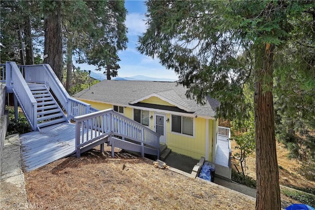 view of front of property featuring a shingled roof, stairway, and a deck