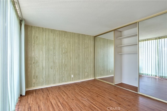 spare room with a textured ceiling, baseboards, and wood finished floors