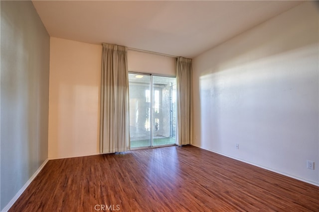 spare room featuring baseboards and wood finished floors