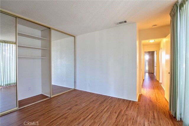 unfurnished bedroom with a closet, a textured ceiling, and hardwood / wood-style floors