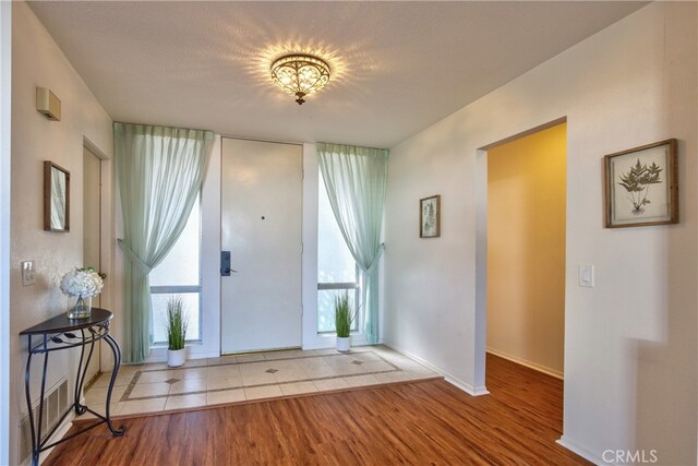 entryway with light wood-type flooring, a wealth of natural light, and a textured ceiling