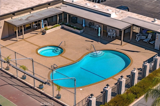 community pool with fence, a community hot tub, and a patio