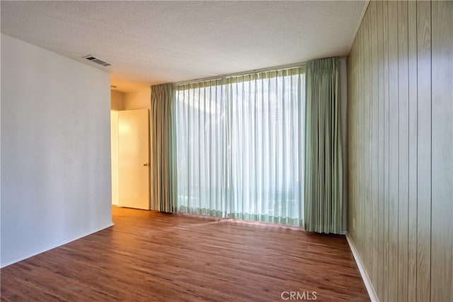 spare room featuring a textured ceiling, wood finished floors, and visible vents