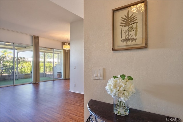 corridor with baseboards, dark wood finished floors, and a textured wall