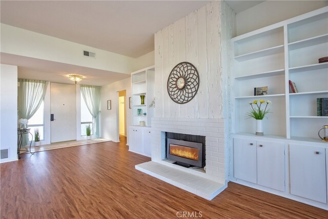 unfurnished living room with a brick fireplace and wood-type flooring