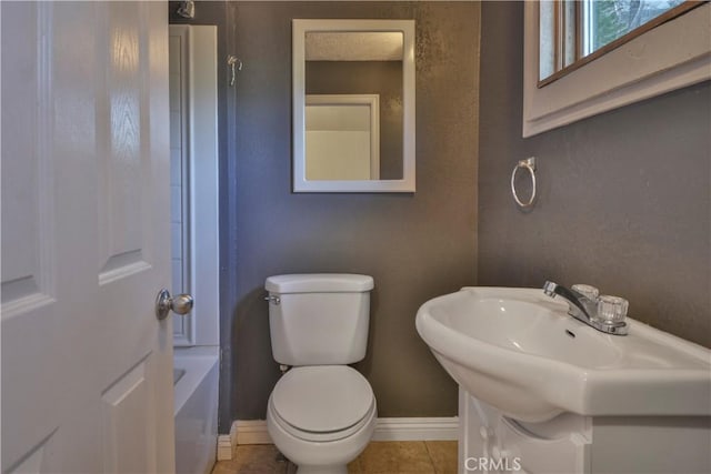 bathroom featuring tile patterned flooring, toilet, and a tub