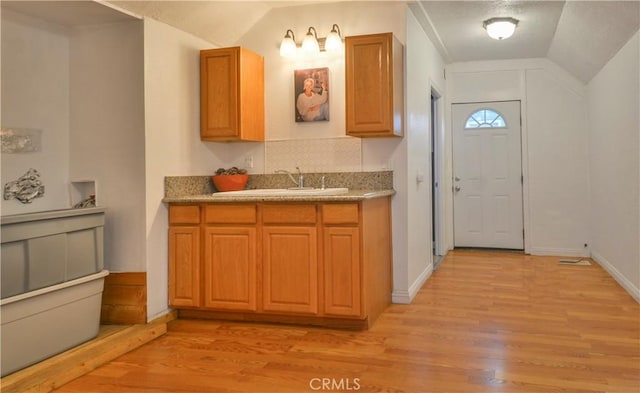 kitchen featuring light hardwood / wood-style floors, lofted ceiling, and sink