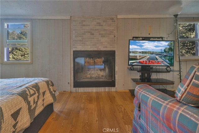 bedroom with wood walls, wood-type flooring, and a fireplace