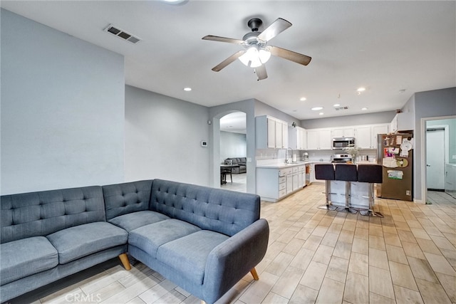 living room featuring light hardwood / wood-style flooring, sink, and ceiling fan