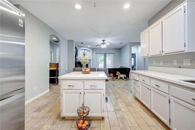 kitchen featuring a kitchen island, ceiling fan, stainless steel refrigerator, white cabinetry, and light hardwood / wood-style flooring