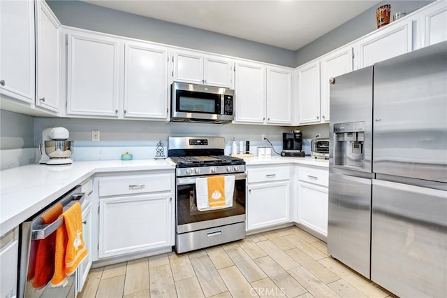 kitchen with stainless steel appliances, light hardwood / wood-style floors, and white cabinets