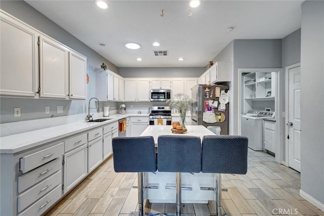 kitchen with a kitchen island, stainless steel appliances, sink, and white cabinetry