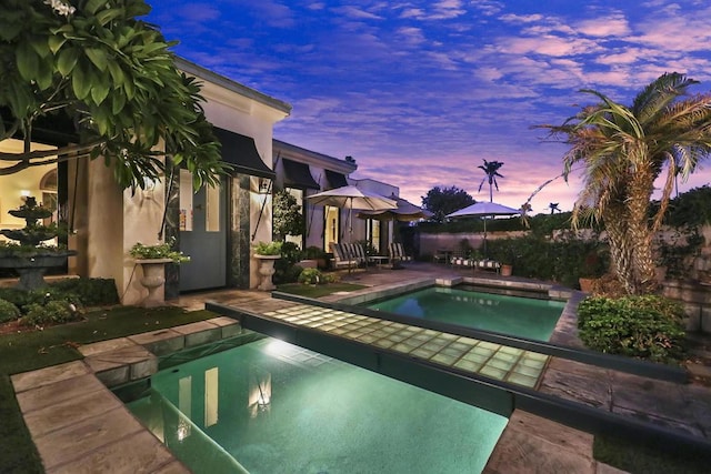 pool at dusk with a patio