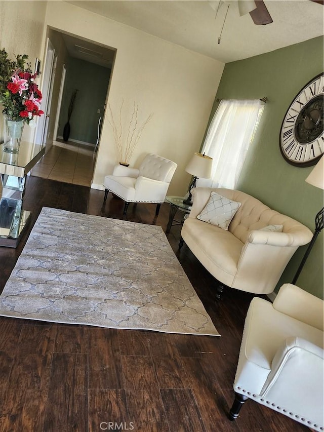 living room featuring dark wood-type flooring and ceiling fan