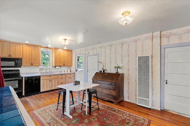 kitchen featuring light hardwood / wood-style flooring, sink, light brown cabinets, and black appliances