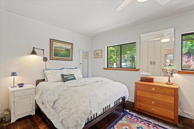 bedroom with dark wood-type flooring, ceiling fan, and multiple windows