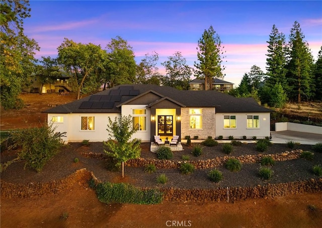 view of front of property with solar panels, french doors, and a patio area