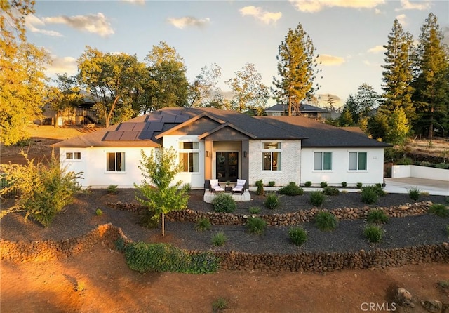 view of front of property featuring solar panels and a patio area