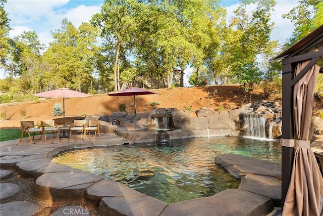 view of swimming pool with pool water feature and a patio