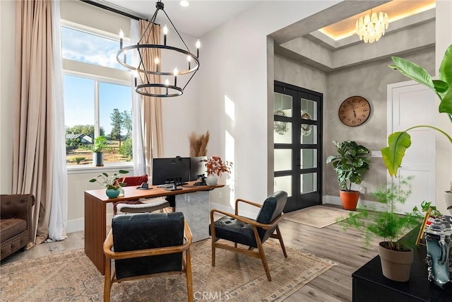 living area featuring french doors, light wood-type flooring, an inviting chandelier, and plenty of natural light