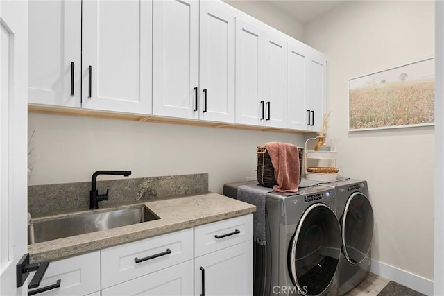 clothes washing area featuring separate washer and dryer, sink, cabinets, and wood-type flooring